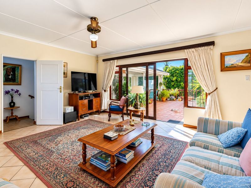 A bright living room featuring tiled floors, a ceiling fan, and large sliding glass doors that provide direct access to an outdoor patio area.