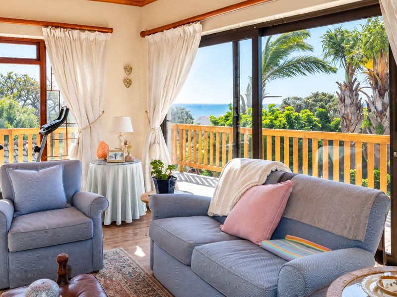 Bright living room featuring large sliding glass doors that open onto a wooden balcony with scenic coastal views.