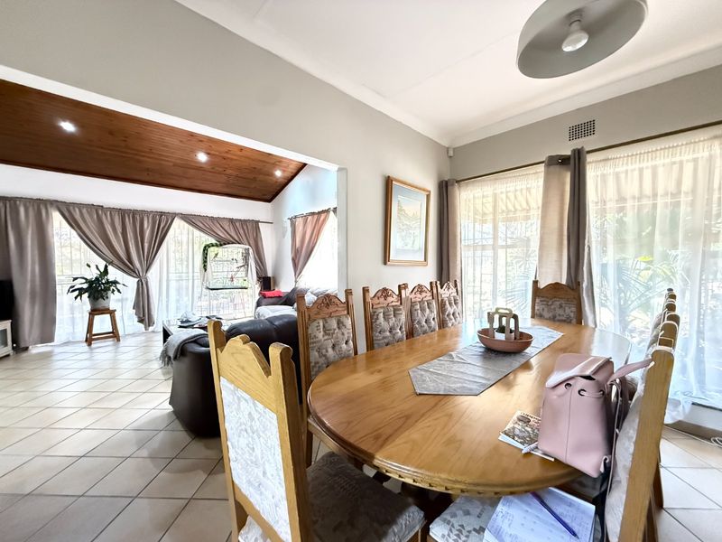 Spacious open-plan dining and living area featuring tiled flooring, a timber-clad vaulted ceiling with recessed lighting, and large sliding doors providing natural light.