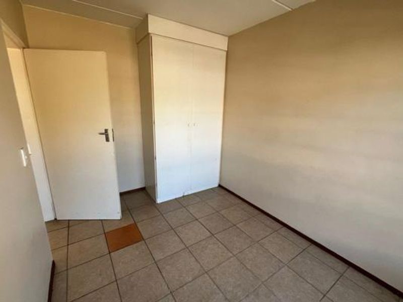 An empty bedroom featuring tiled flooring and a built-in wardrobe, presenting a blank canvas for potential interior updates.