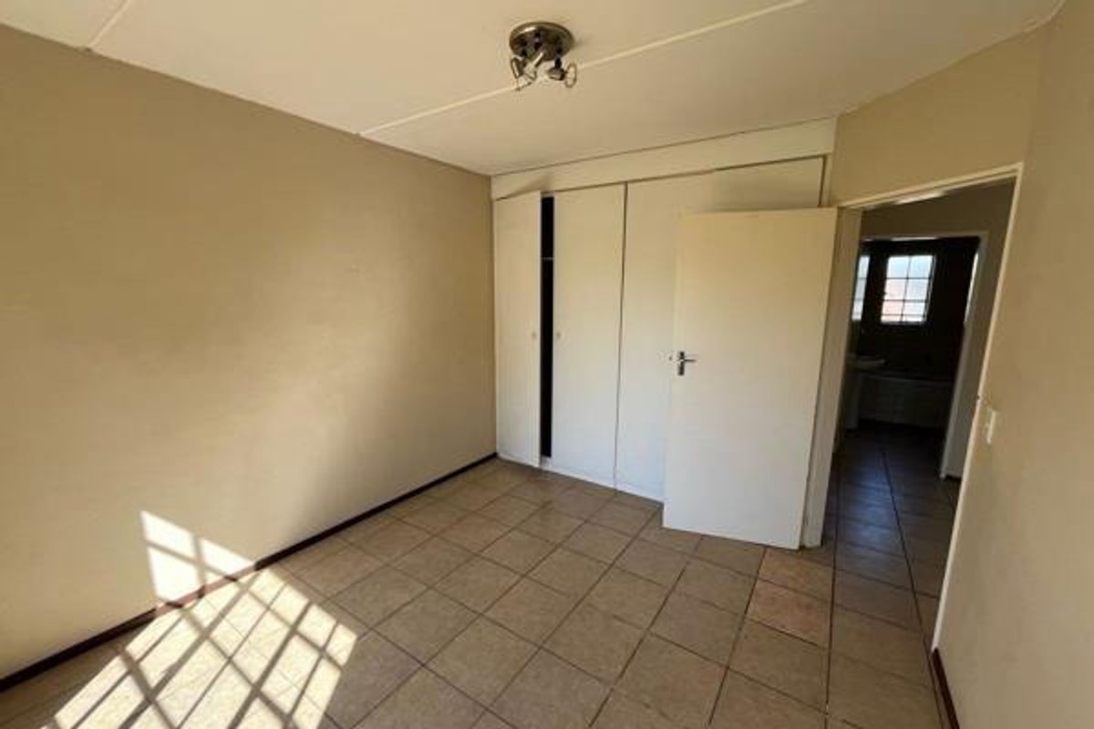An empty bedroom featuring tiled flooring and built-in cupboards, offering a blank canvas for renovation or staging.