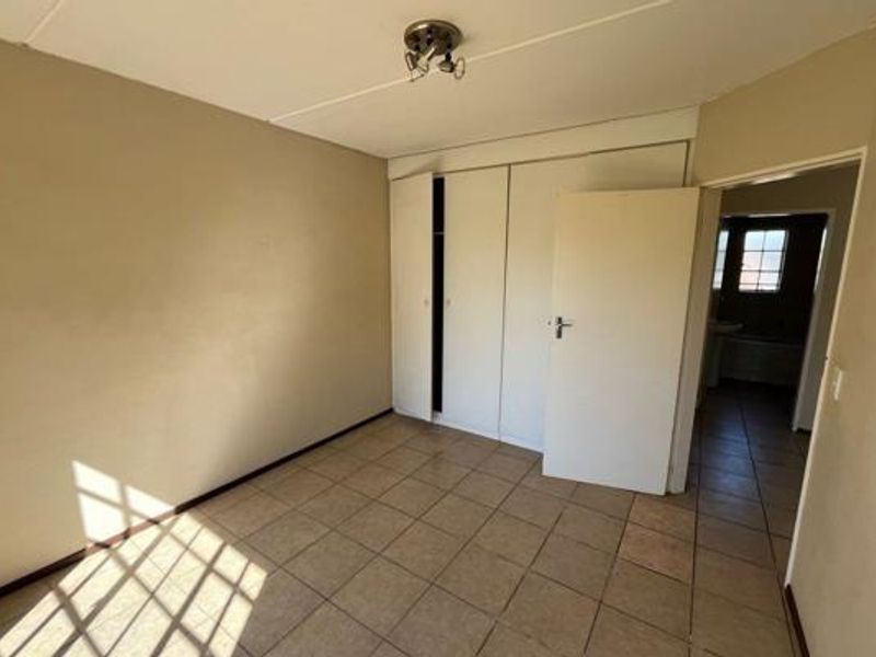 An empty bedroom featuring tiled flooring and built-in cupboards, offering a blank canvas for renovation or staging.