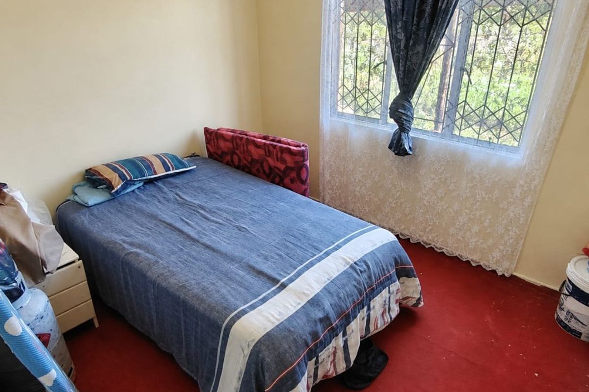 A bedroom featuring a window with security bars and red carpeting, offering a functional space ready for cosmetic updates.