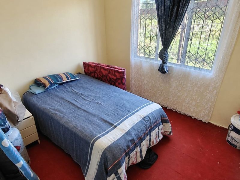 A bedroom featuring a window with security bars and red carpeting, offering a functional space ready for cosmetic updates.