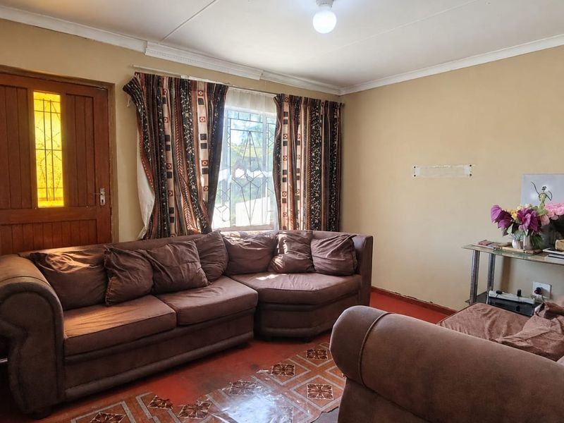 A living room featuring a timber door with leadlight glass, coved ceilings, and patterned floor tiles, requiring cosmetic updates to improve the overall aesthetic.