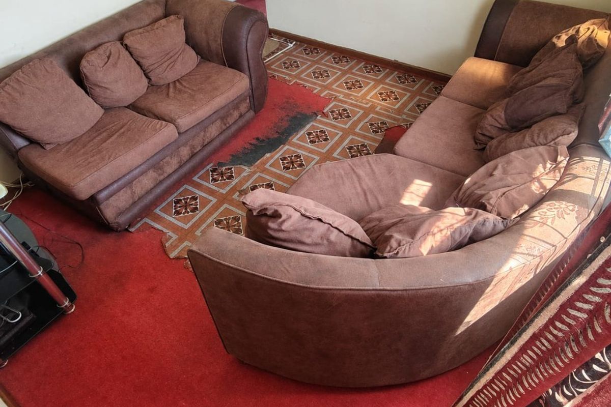 A living room area featuring patterned floor tiles and a red carpet, requiring updates to finishes to modernize the space.
