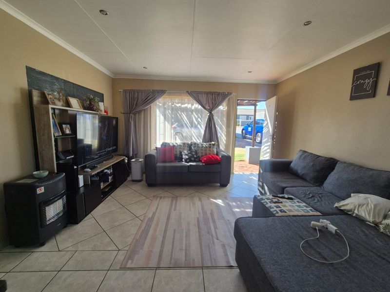 A comfortable living room featuring tiled flooring, recessed downlighting, and direct access to the exterior through a sliding door.