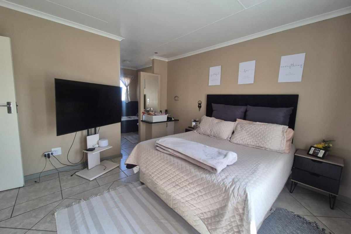 A bedroom featuring tiled flooring, a built-in vanity area, and an en-suite bathroom layout.