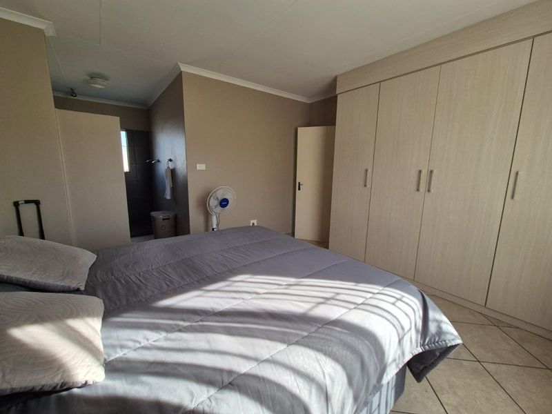 A bedroom featuring built-in cupboards, tiled flooring, and direct access to an en-suite bathroom.
