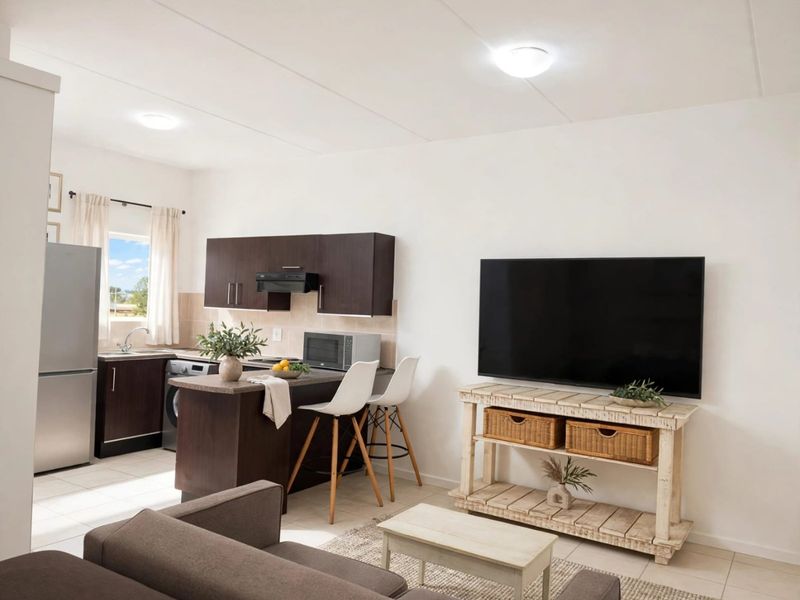 Open-plan living area featuring a compact kitchen with dark wood cabinetry, tiled flooring, and a seamless flow into the lounge space.