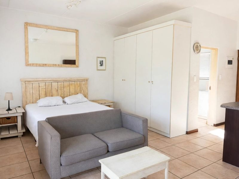 A bedroom featuring tiled flooring and a large built-in wardrobe, with direct access to an adjoining room.