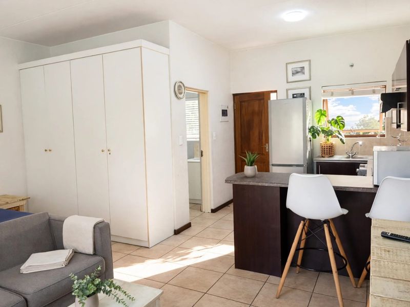 Open plan living area featuring tiled floors, a kitchen island with breakfast bar, and ample built-in storage cupboards.