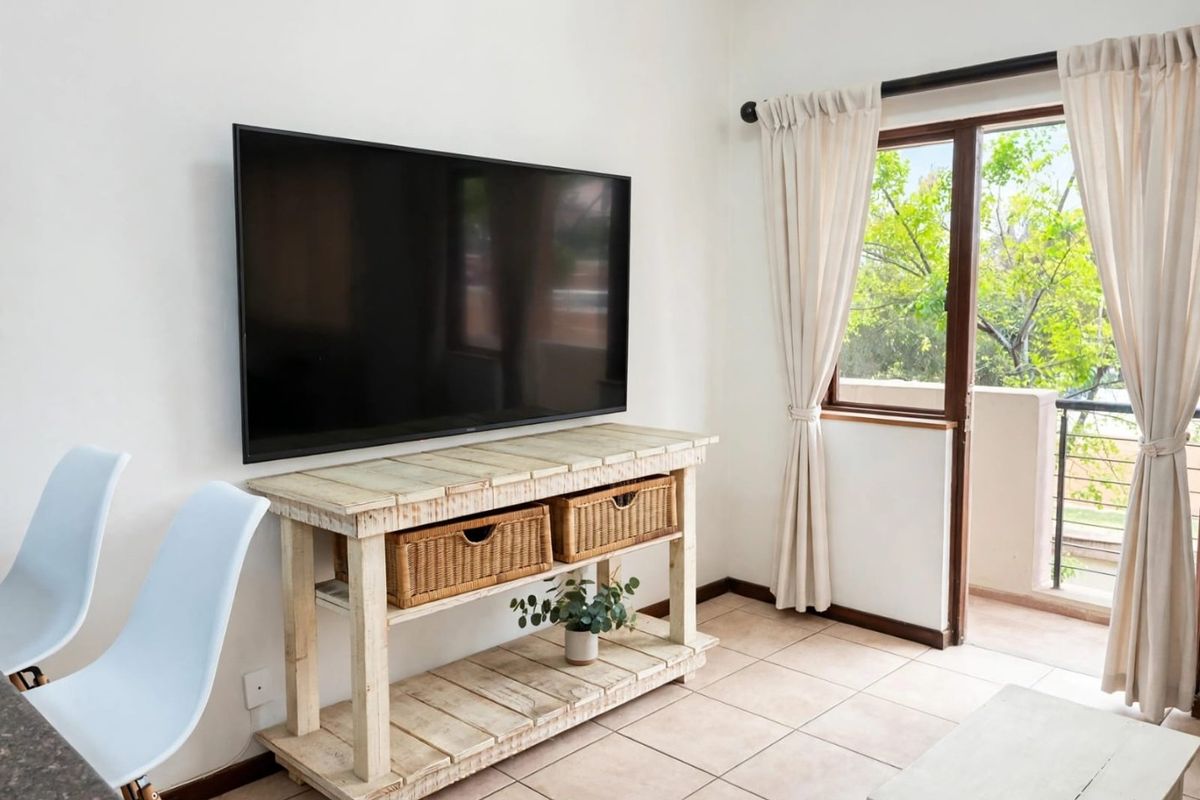 A bright living room featuring tiled flooring and a sliding glass door providing access to an outdoor balcony area.
