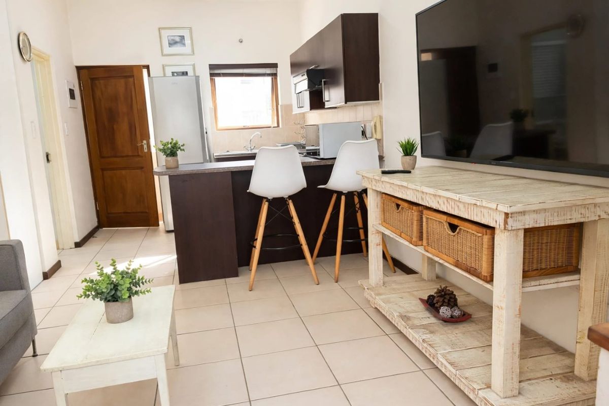Open plan living area featuring tiled flooring and a compact kitchen with dark cabinetry and a breakfast counter.