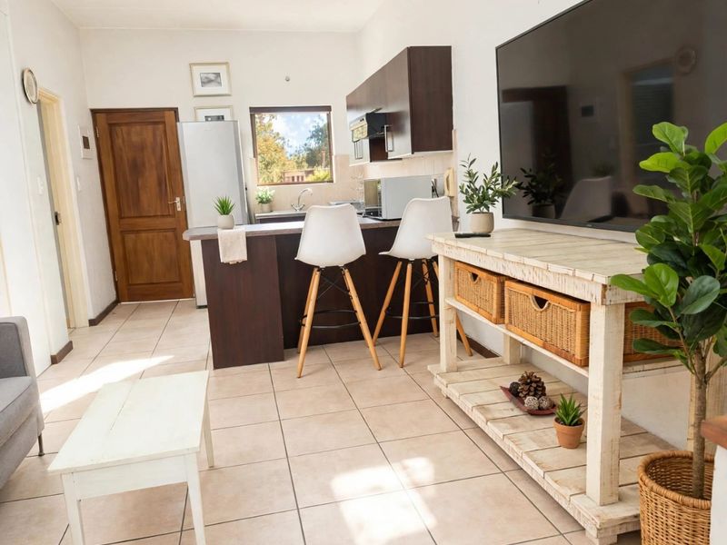 Open-plan living area featuring a functional kitchen with breakfast bar, tiled flooring, and direct access to the rest of the apartment.