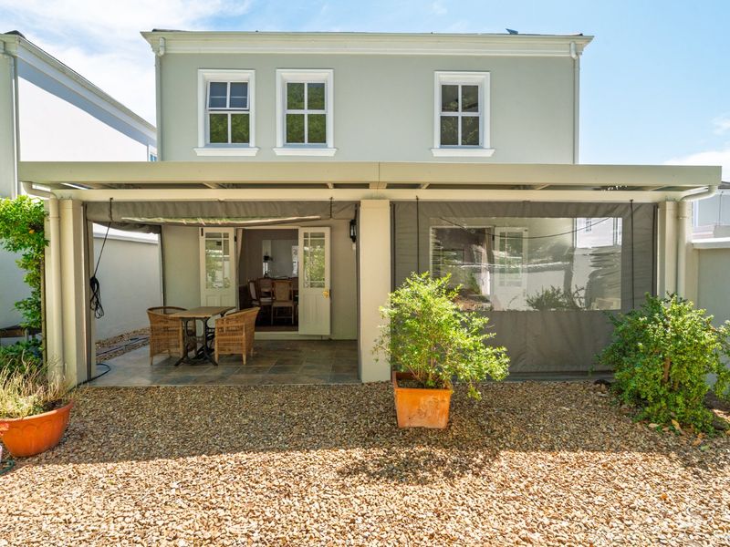 Rear view of the property featuring a covered patio with tiled flooring, retractable outdoor blinds, and a low-maintenance gravel garden area.