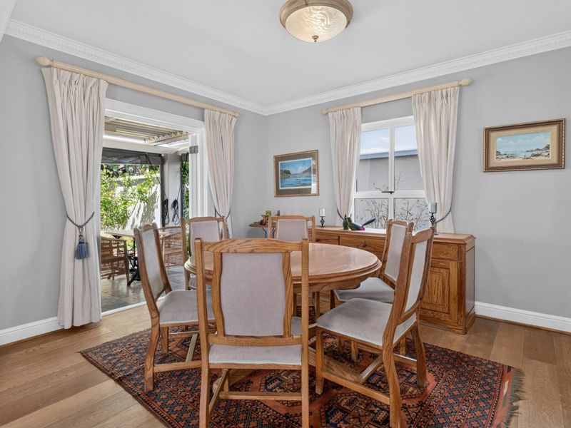 A bright dining room featuring hardwood flooring, crown molding, and direct access to an outdoor patio area through sliding glass doors.