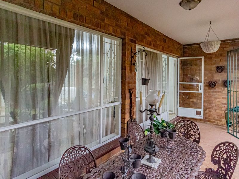 A covered patio area featuring exposed brick walls, tiled flooring, and large sliding glass doors providing access to the interior living space.