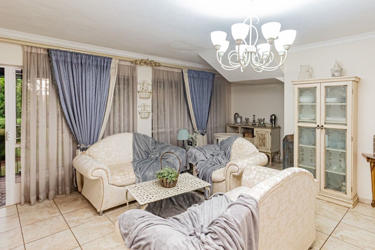 A well-maintained living room featuring tiled flooring, a decorative chandelier, and a sliding glass door providing access to the outdoor area.