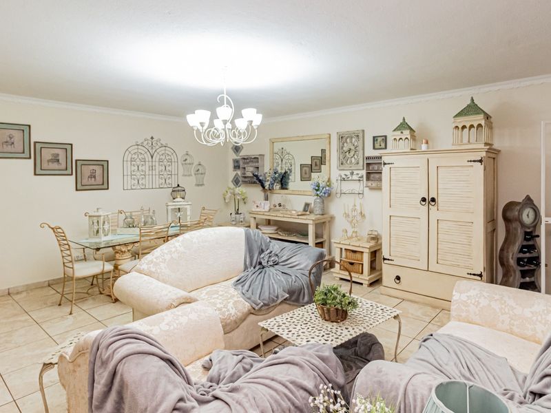 Open plan living and dining area featuring tiled flooring, decorative coving, and an arched entryway, providing a versatile space for relaxation and entertaining.
