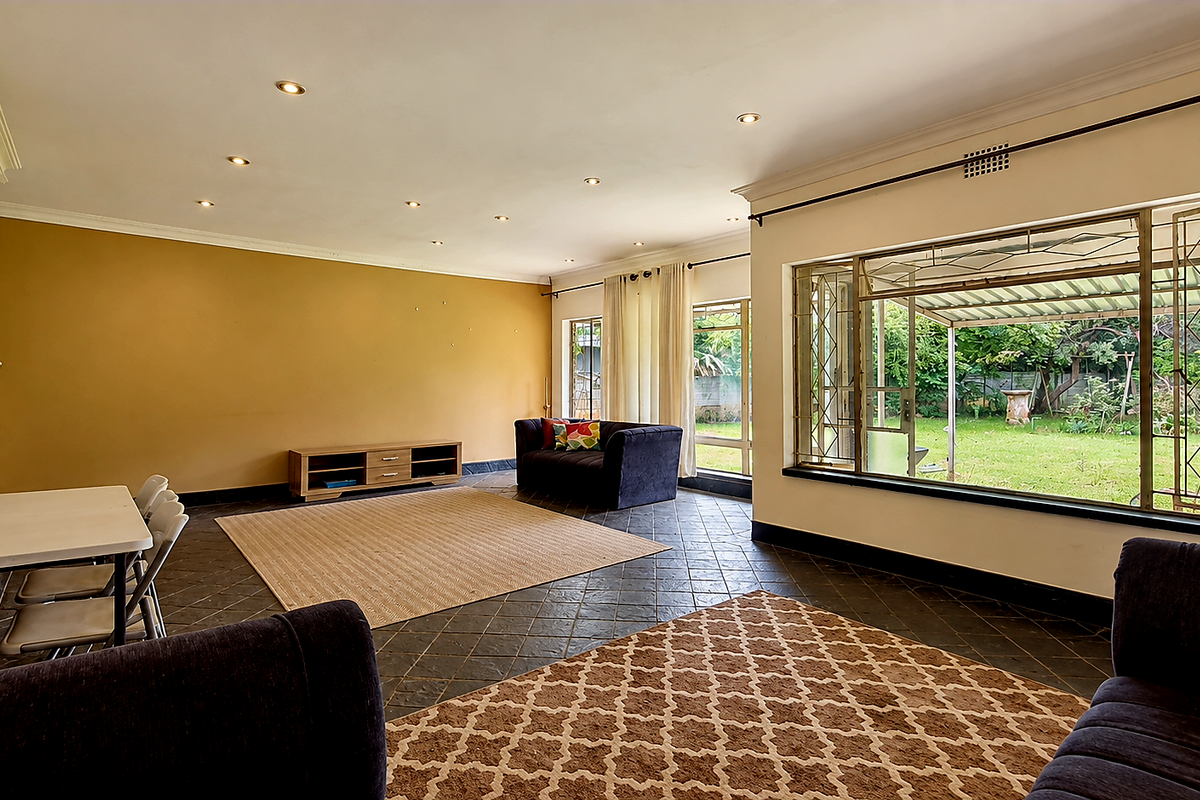 Spacious living room featuring tiled flooring, recessed lighting, and large windows providing natural light and access to the rear garden.
