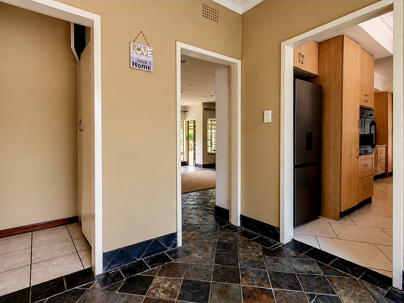 A tiled hallway providing access to adjacent living areas and a kitchen featuring built-in cabinetry and integrated appliances.