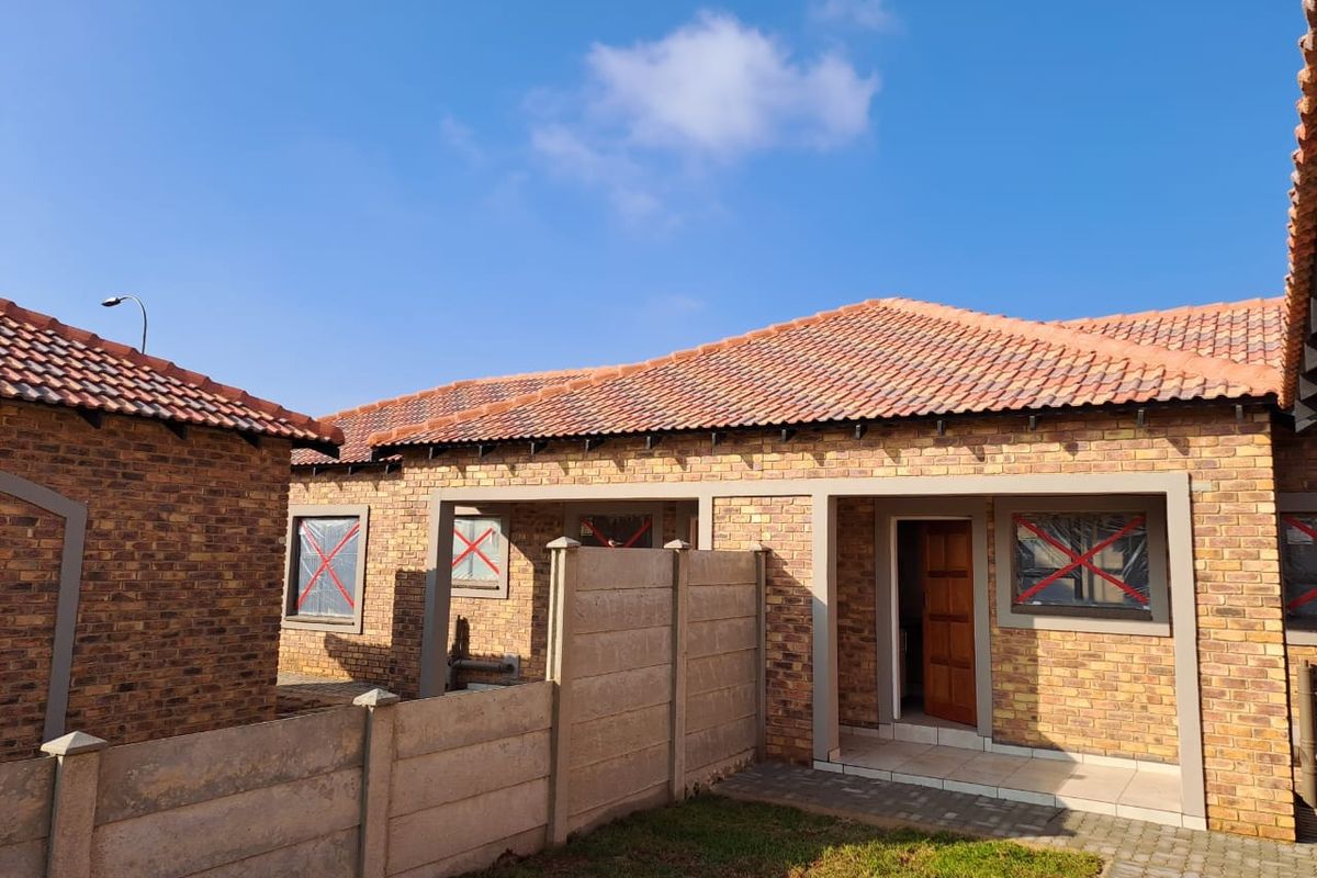 Rear view of a face brick commercial property featuring a tiled roof, paved walkway, and secure precast boundary walling.