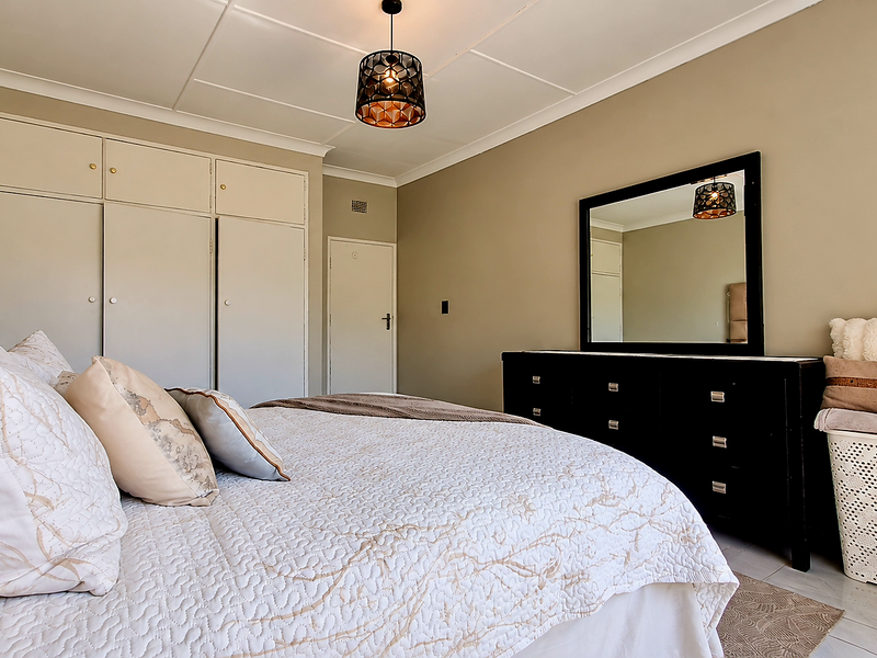 A well-maintained bedroom featuring built-in cupboards, neutral wall tones, and tiled flooring, offering a clean and functional living space.
