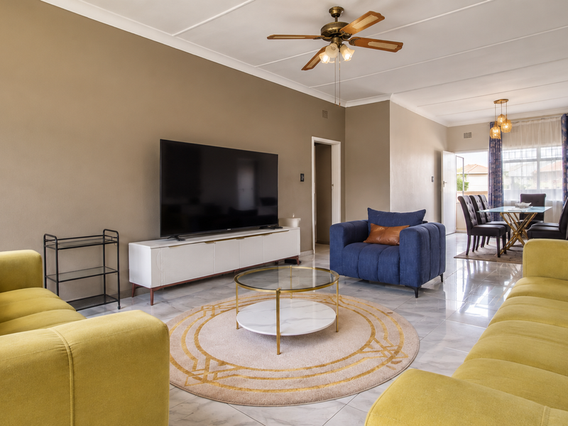 Spacious open-plan living and dining area featuring polished tiled flooring, a ceiling fan, and neutral wall tones, creating a bright and functional living space.