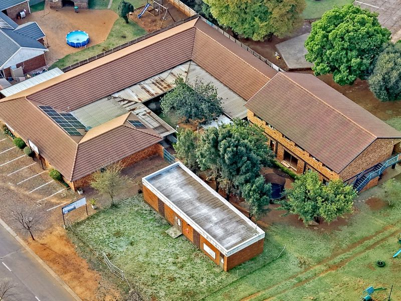 Aerial view of a commercial property complex featuring multiple brick buildings, tiled roofing, solar panels, and dedicated parking areas.