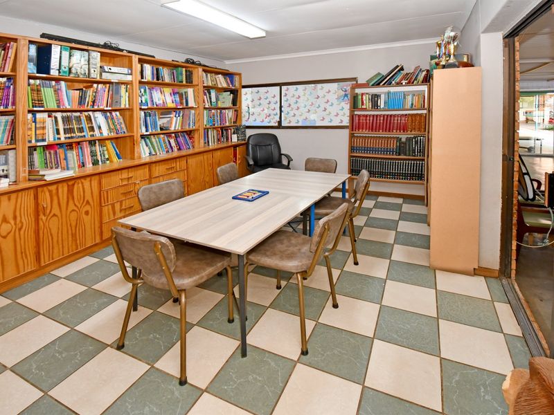 A functional office or study space featuring extensive built-in wooden shelving and durable checkered ceramic floor tiles.