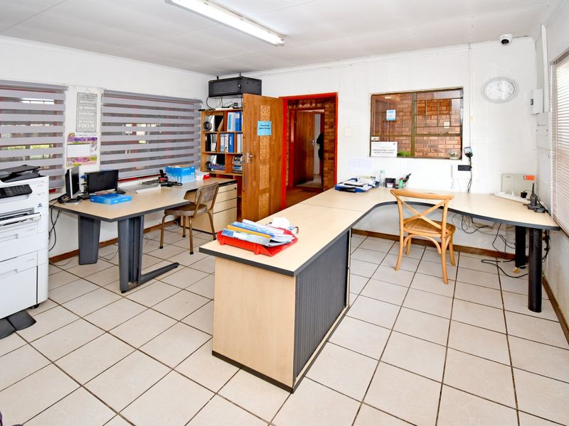 Functional commercial office space featuring ceramic tiled flooring, built-in desk configurations, and integrated security infrastructure.