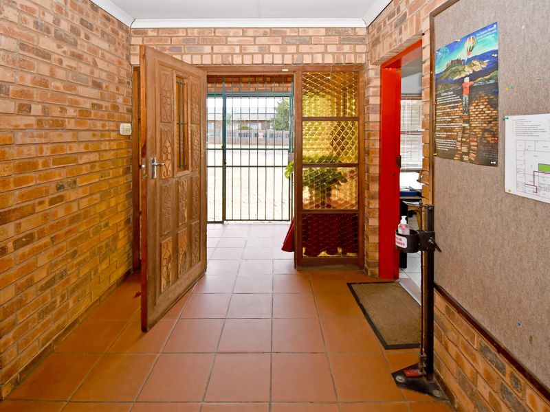 Entrance foyer featuring exposed brick walls, tiled flooring, and a secure wooden door with decorative glass paneling.