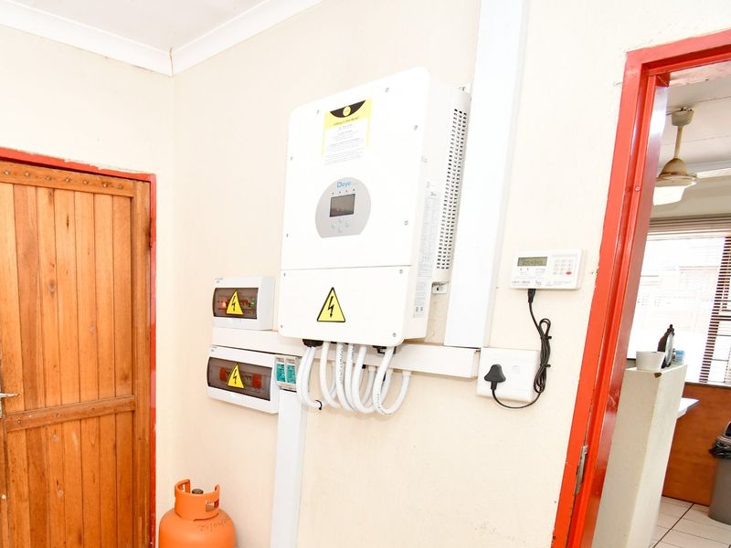 Utility area featuring a wall-mounted solar inverter system and electrical distribution boards, providing essential power infrastructure for the commercial property.