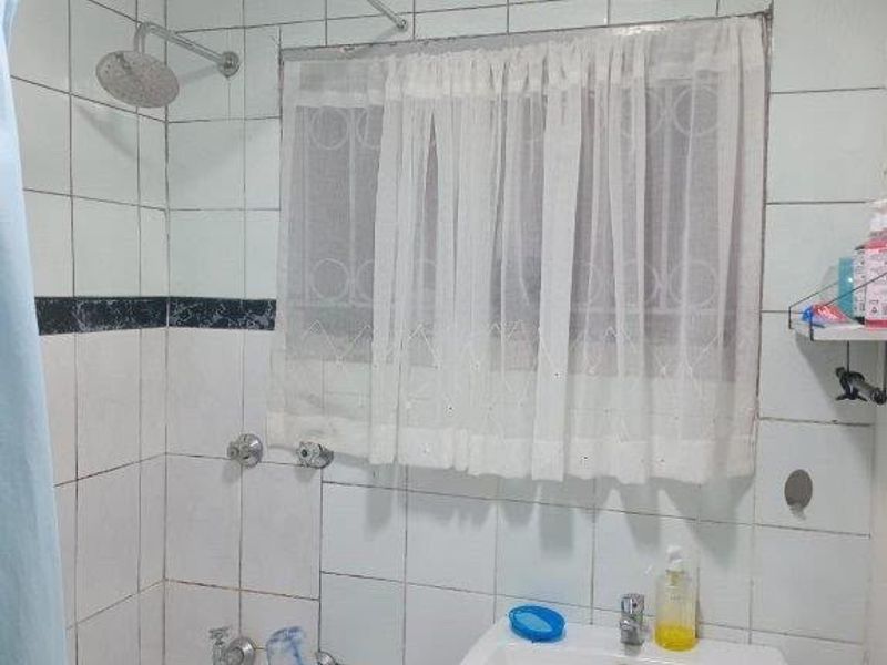 A functional bathroom featuring a pedestal washbasin, bathtub, and shower head with tiled wall finishes.