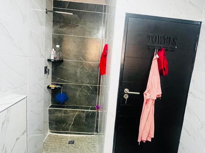 A modern bathroom featuring a walk-in shower with a rain shower head, built-in bench, and marble-effect wall tiling.