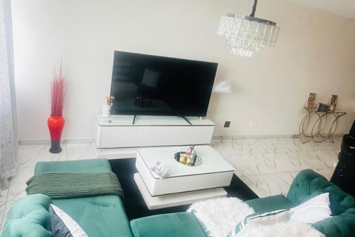 A bright living room featuring polished marble-look floor tiles and a decorative crystal chandelier, creating a modern and elegant atmosphere.