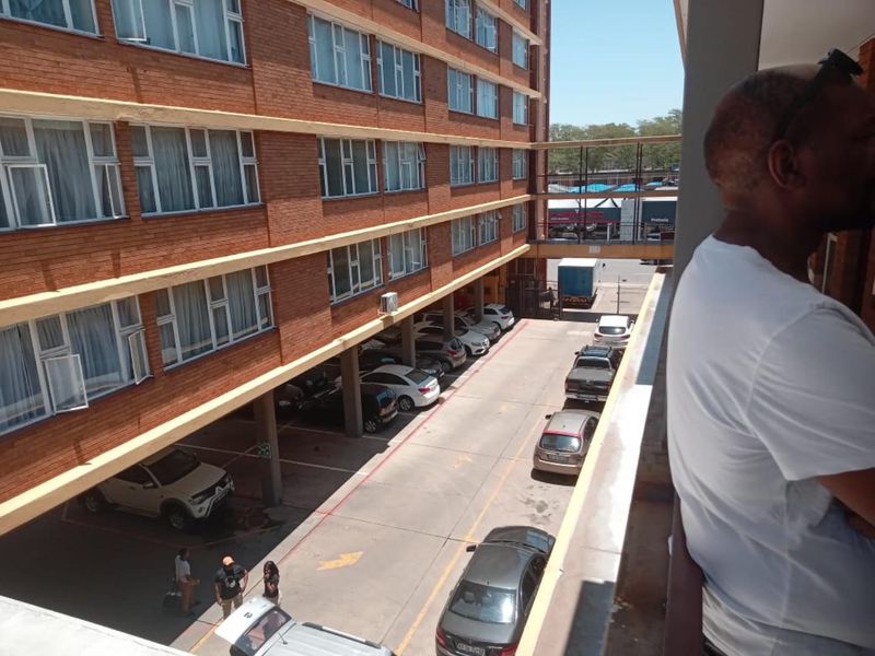 View from a balcony overlooking the apartment complex parking area and brick building facade.