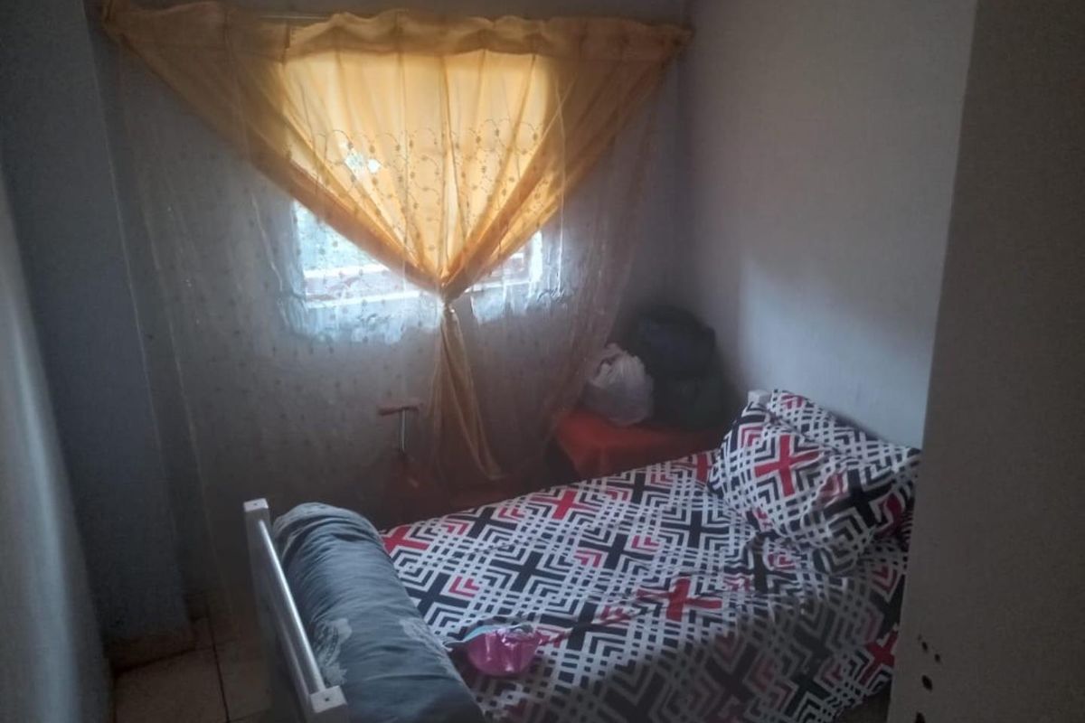 A compact bedroom featuring tiled flooring and a window, providing a functional space for rest.