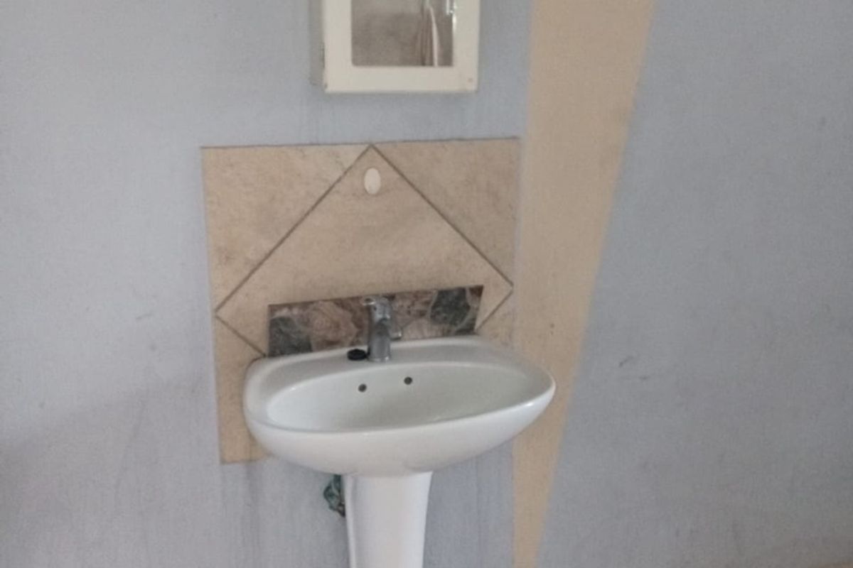 A basic bathroom area featuring a pedestal basin, tiled splashback, and a wall-mounted medicine cabinet with ceramic floor tiling.