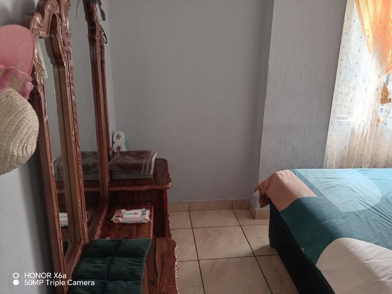 A bedroom featuring tiled flooring and neutral wall finishes, providing a functional space for rest.