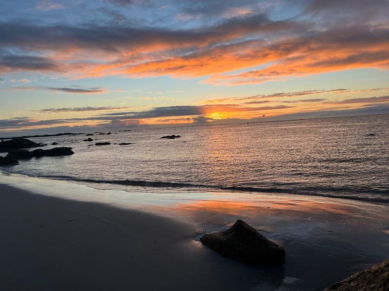 A scenic sunset view over the ocean and rocky coastline, highlighting the natural beauty of the property's surroundings.