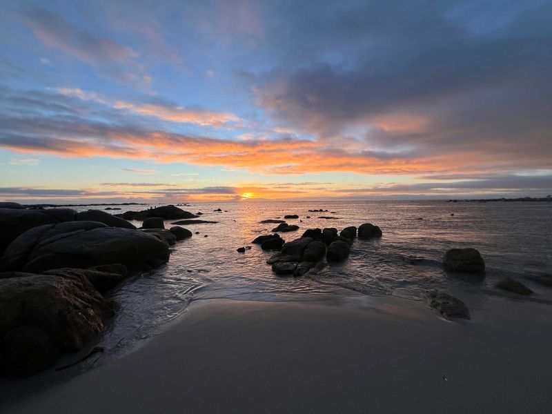 A scenic coastal view featuring a rocky shoreline at sunset, highlighting the natural beauty and tranquil atmosphere of the property's surroundings.