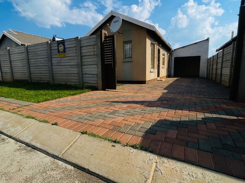 Front view of a residential property featuring a paved driveway, precast boundary wall, and an attached garage.