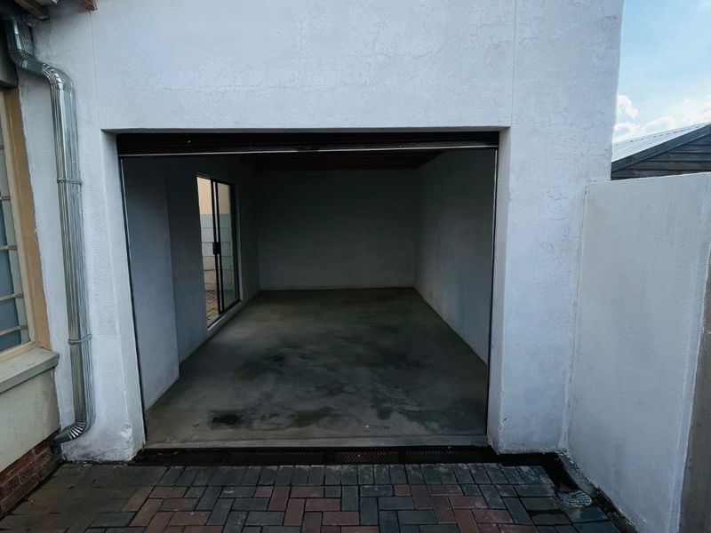 A functional garage space featuring a concrete floor, paved exterior approach, and a side sliding door for additional access.