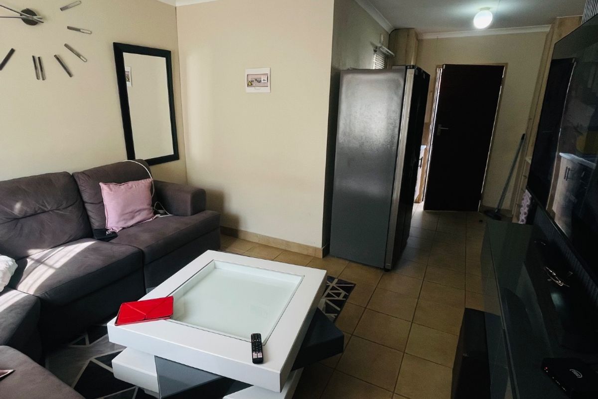 A living room area featuring tiled flooring and neutral wall finishes, providing a functional space with direct access to the home's interior layout.