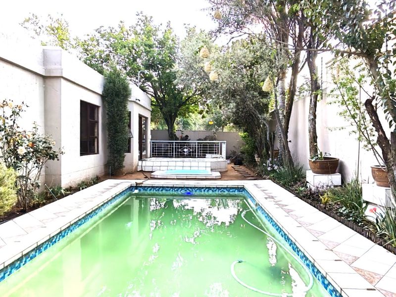 Outdoor pool area featuring a tiled surround, raised patio section with metal balustrade, and perimeter boundary walls.
