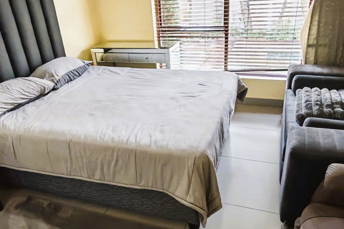 A bedroom featuring tiled flooring and venetian blinds, providing a functional space with natural light.