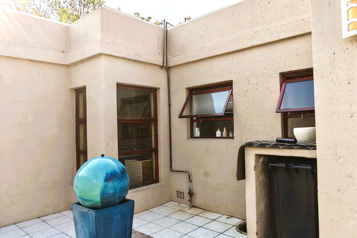A private rear courtyard area featuring tiled flooring, plastered walls, and multiple top-hung windows, offering a functional outdoor space.