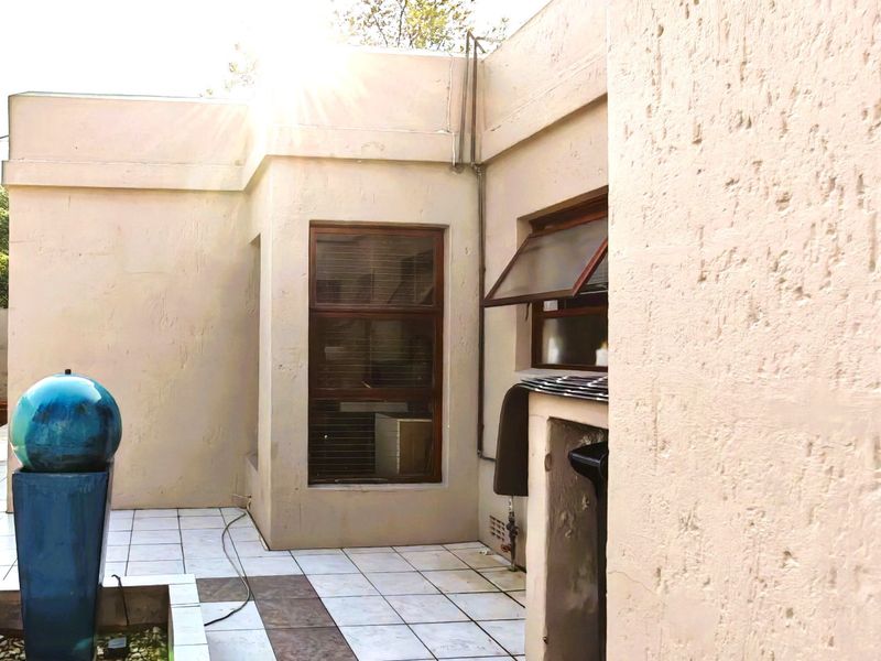 A paved outdoor patio area featuring tiled flooring, timber-framed windows, and exterior wall finishes, providing a functional space for outdoor living.